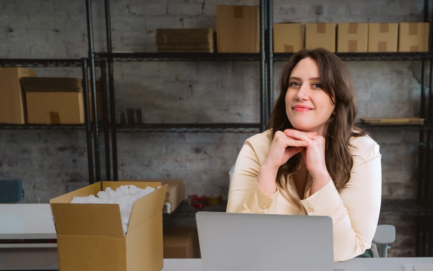 Woman looking happy with laptop in ecommerce workspace