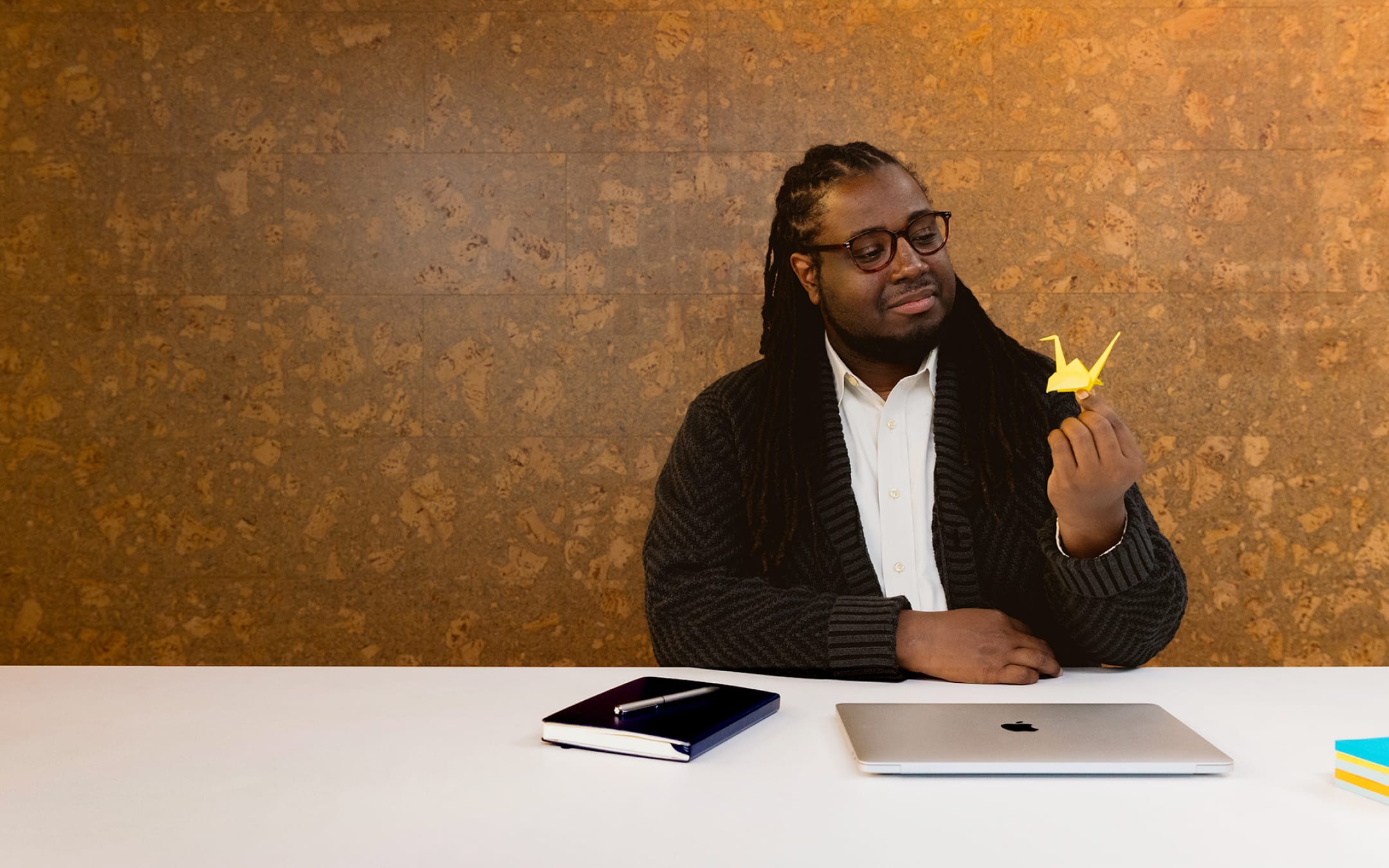 Happy man with closed laptop looking at origami crane