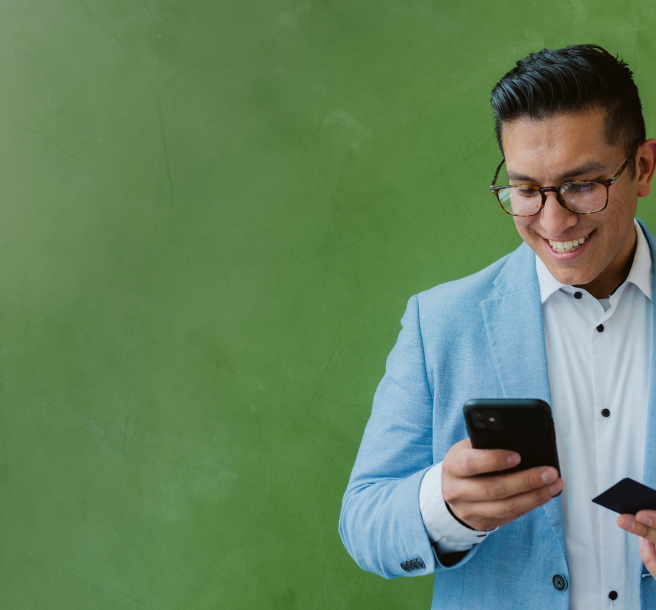 Man in blue blazer looking at phone and holding credit card