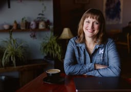 woman smiling sitting at table arms crossed