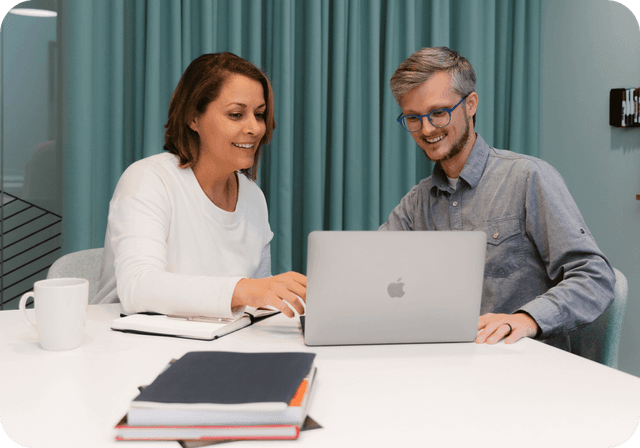 man and woman have friendly discussion over something on a laptop