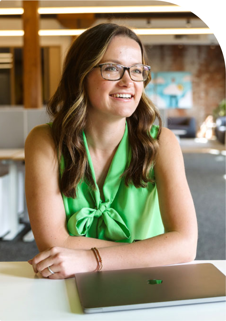 woman with glasses in green blouse sitting behind a closed laptop talking about WordPress Hosting