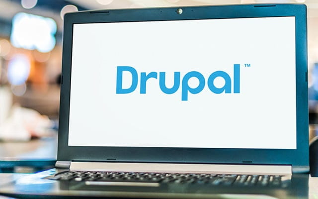 Laptop on a table displaying Drupal's logo