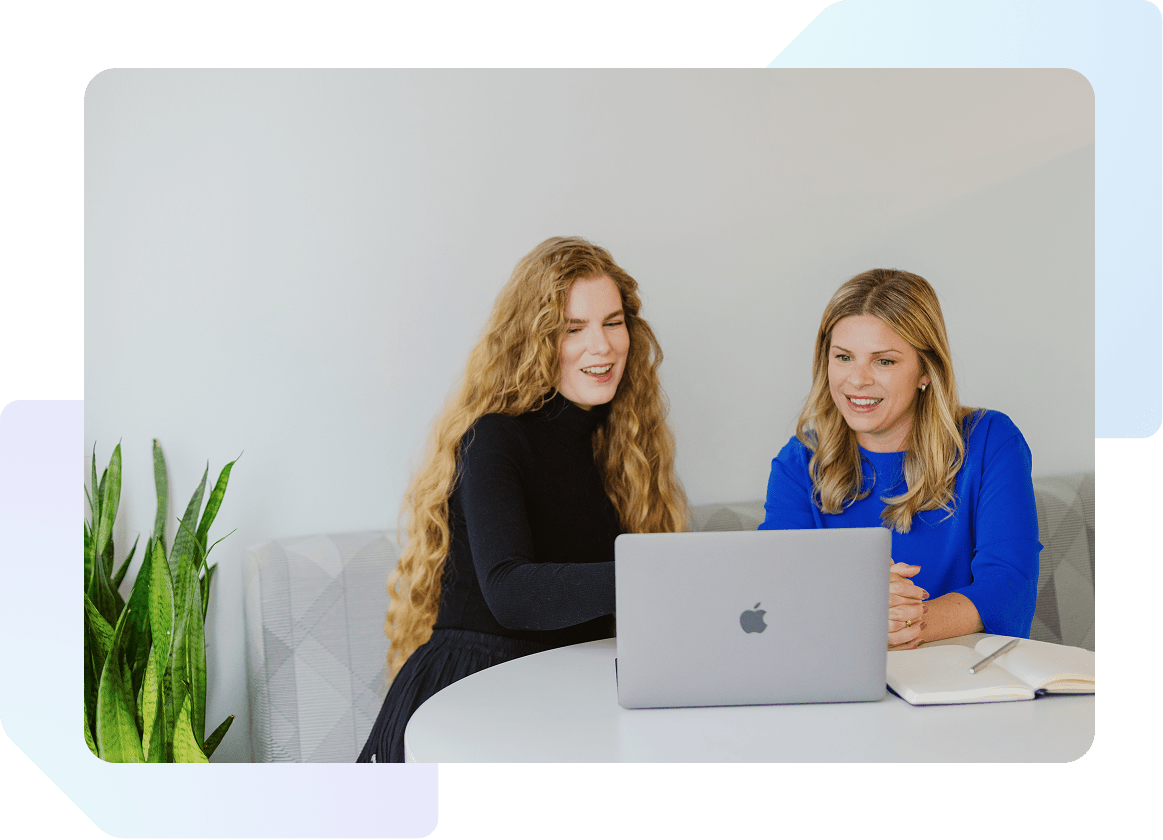 Two women at a table looking at a laptop together