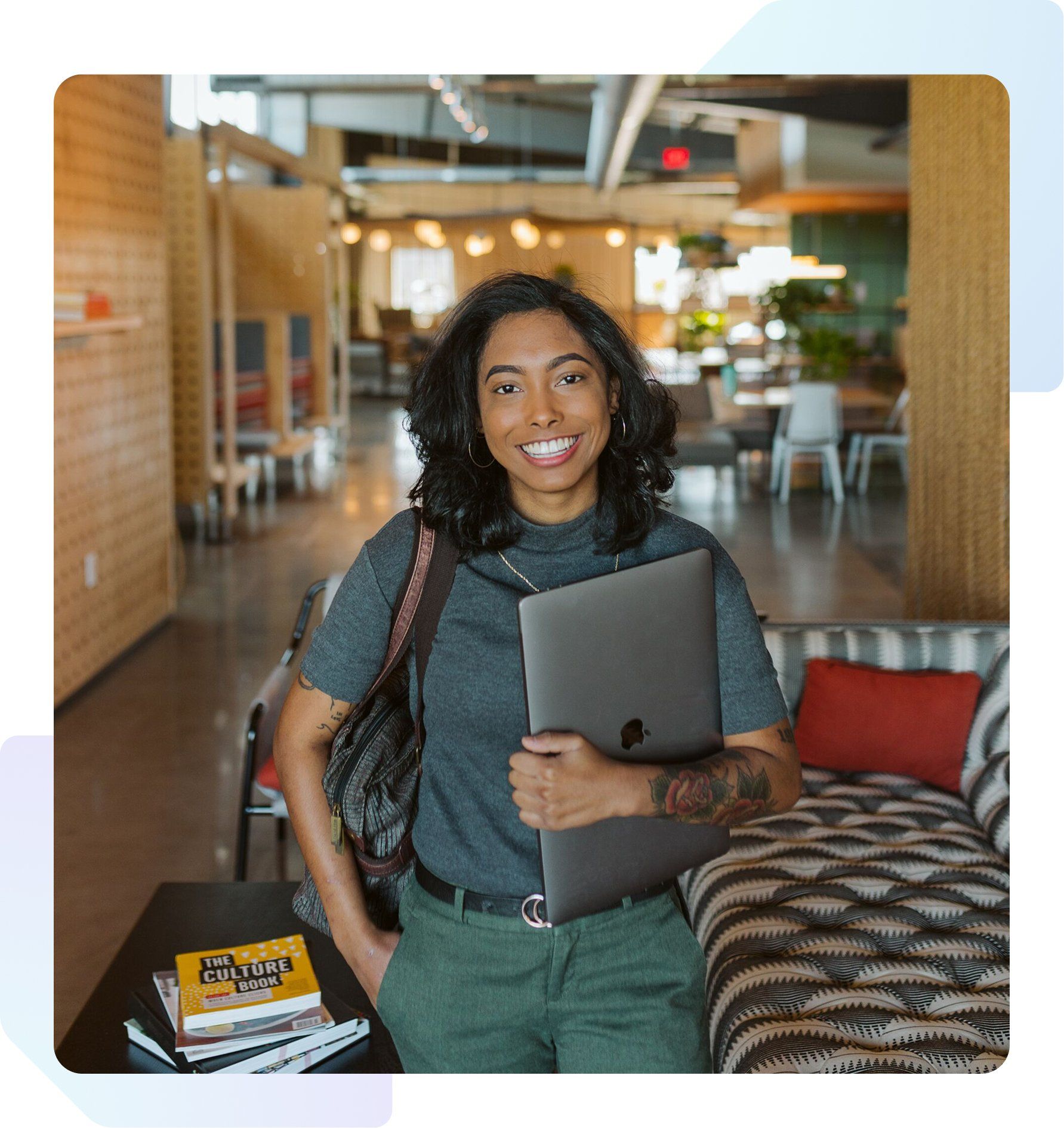 Woman standing and smiling holding a closed laptop