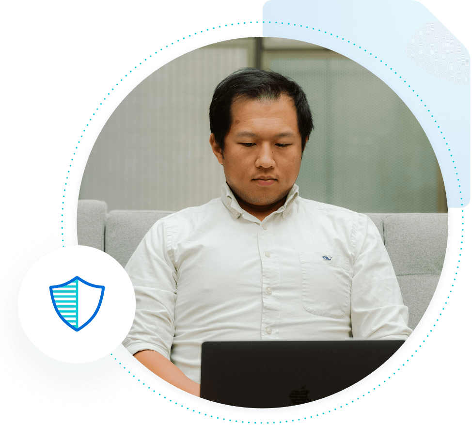 Ethnic man sitting at a laptop with a Security shield icon hovering near him