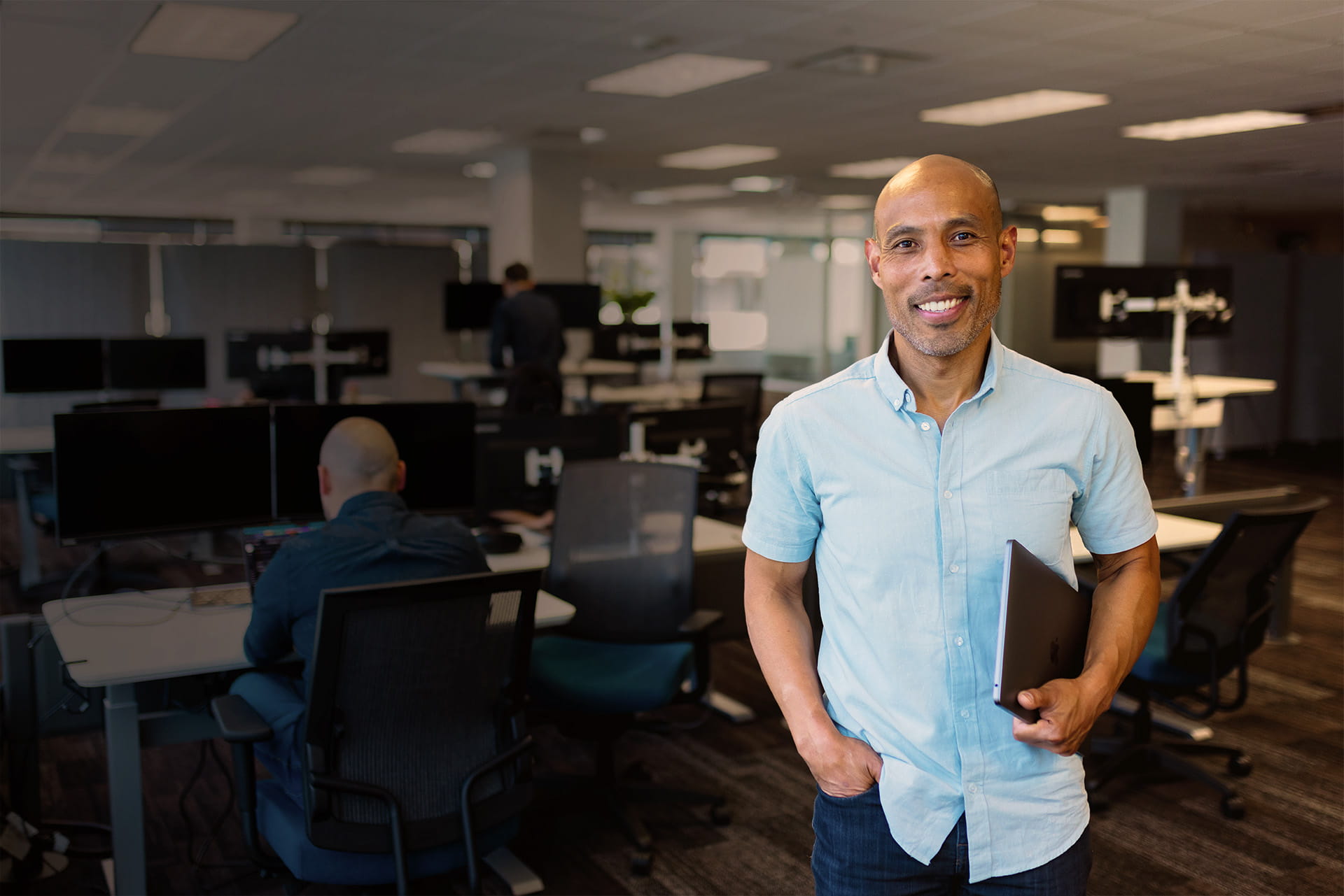 Manager, Developer Relations at WP Engine, man with hand in pocket holding laptop and smiling in office setting