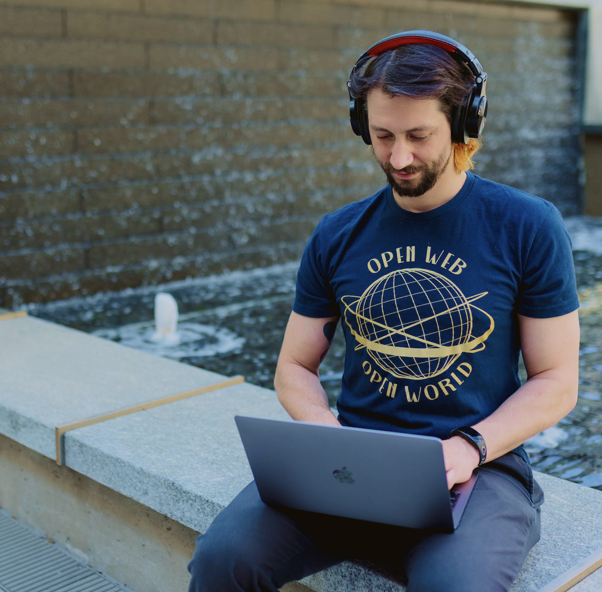 man typing about "WordPress hosting" on Apple laptop and wearing headphones