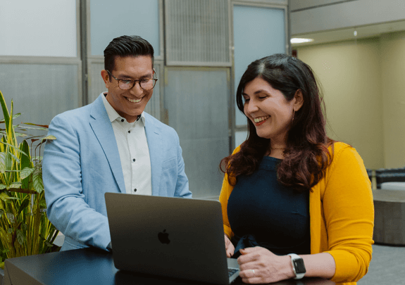 Two of WordPress professionals look at a laptop.