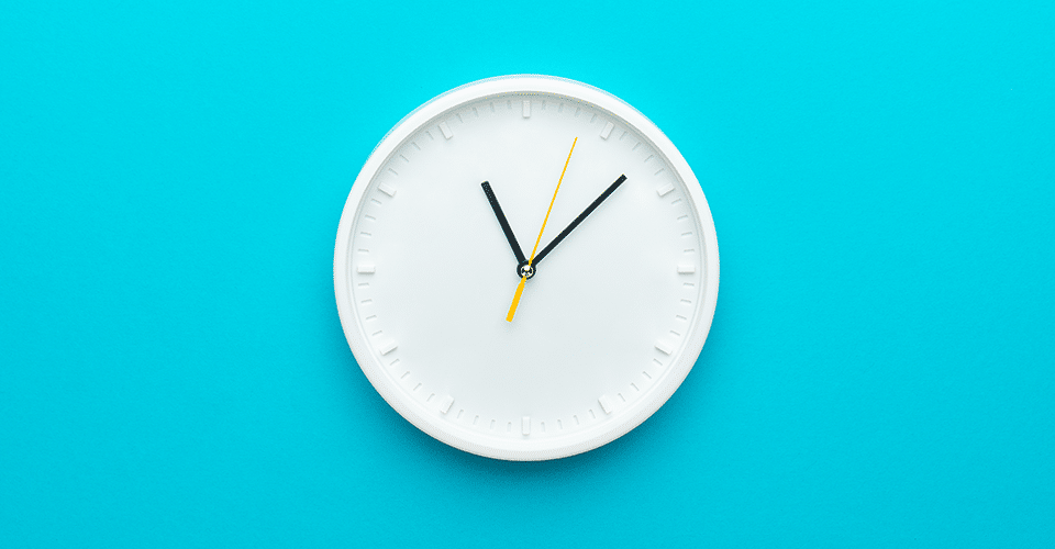 white analog clock with black hands on a blue background
