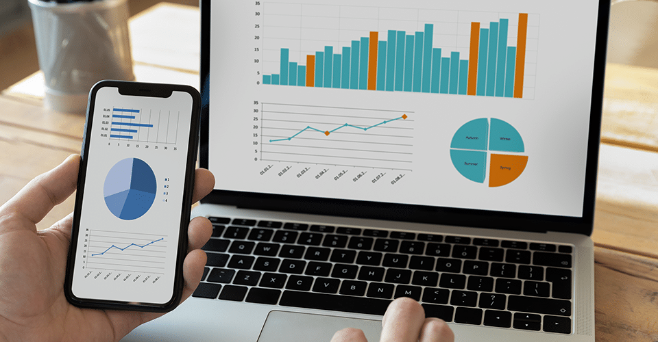 a person reviews a series of charts on both a laptop and mobile device