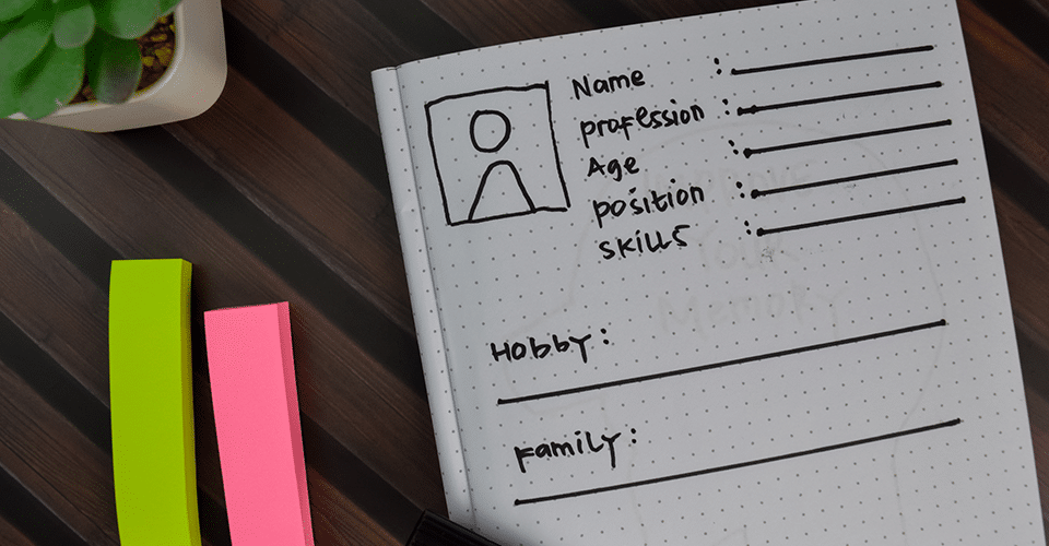 A designer sketches out a the specifics of a user persona at a wooden desk.