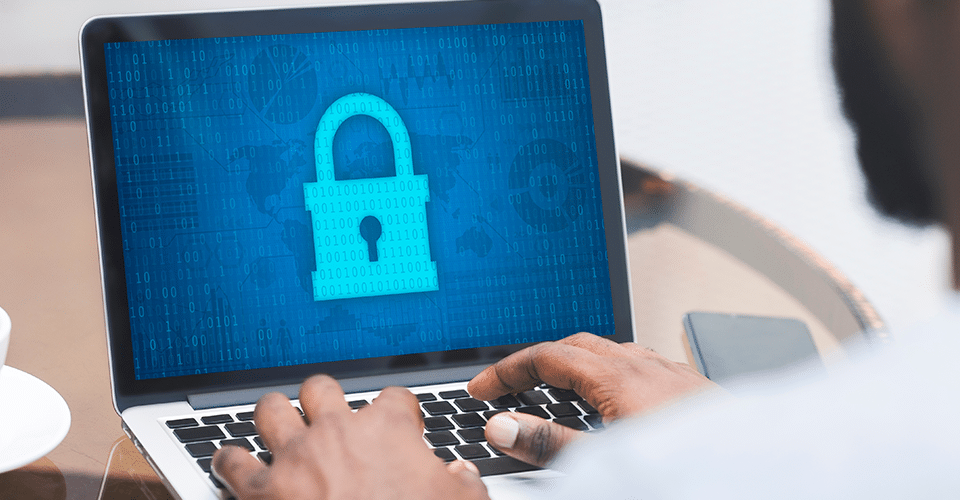a person working on cybersecurity using a laptop which displays a large padlock icon