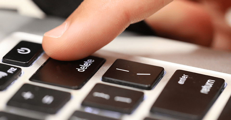 WordPress Delete All Posts in Bulk. a person presses the Delete button on a keyboard
