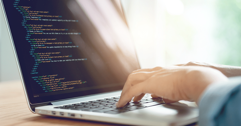 Using Markdown in WordPress. image depicts a person working on code on a laptop