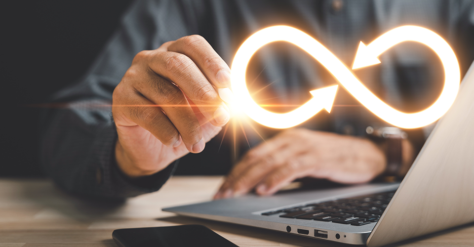 How to Add Infinite Scroll to WordPress. image depicts a person sitting in front of a laptop while tracing a yellow infinity symbol in the air