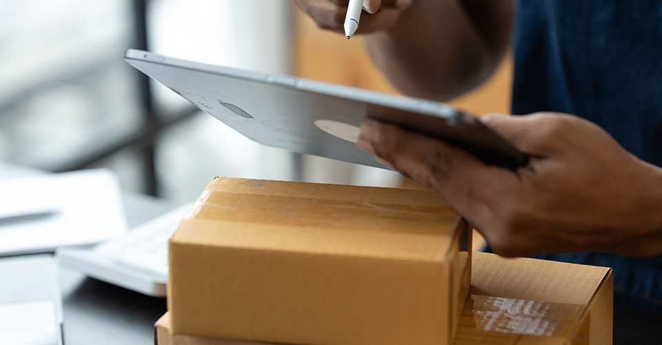 a warehouse worker checks the shipping specifications for a package. WordPress dropshipping