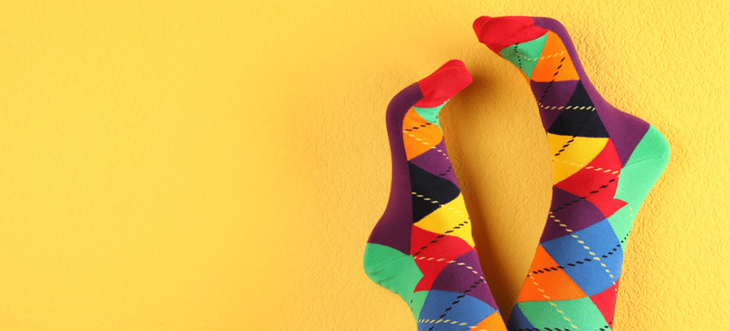 someone wearing colorful socks kicks their feet up on a yellow wall