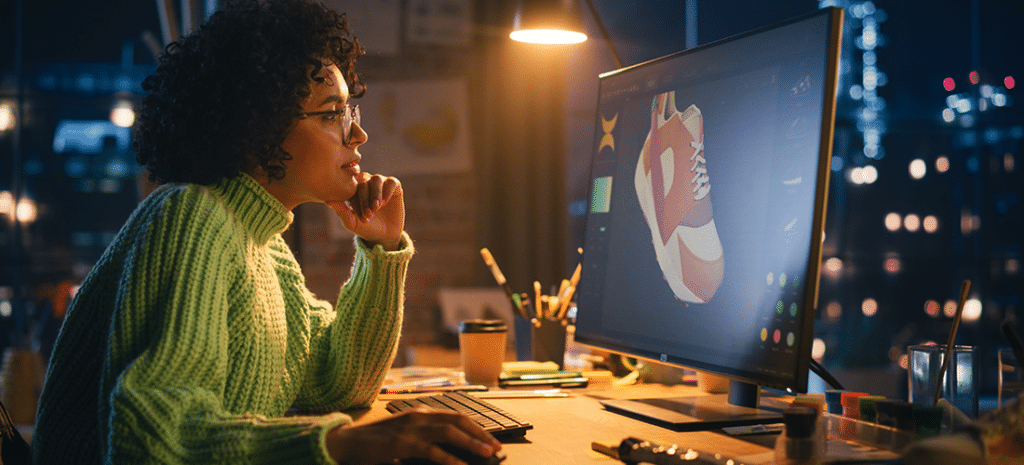 a woman wearing glasses and a green sweater reviews a 3D model of a shoe for use on an eCommerce website