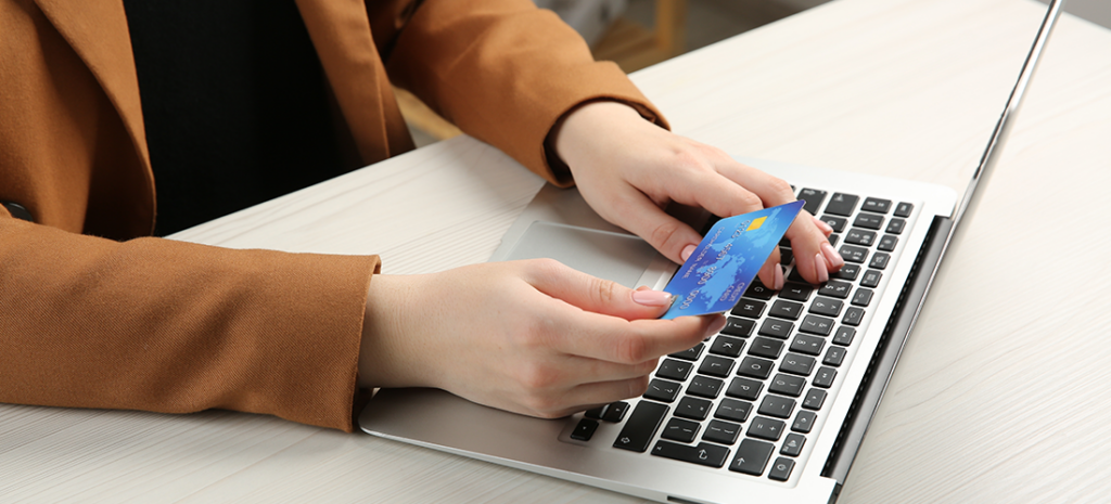 a woman uses a credit card to buy from an eCommerce site on a laptop