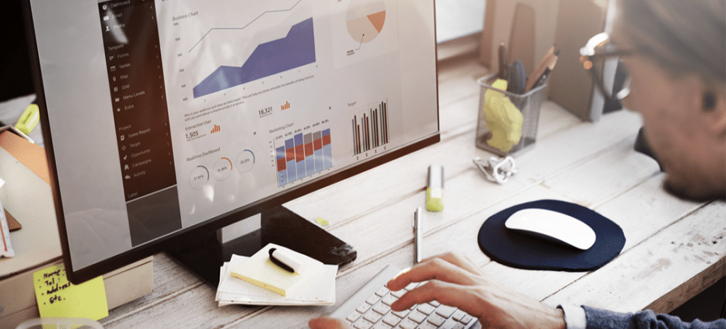 a man looks at an analytics dashboard on a desktop computer