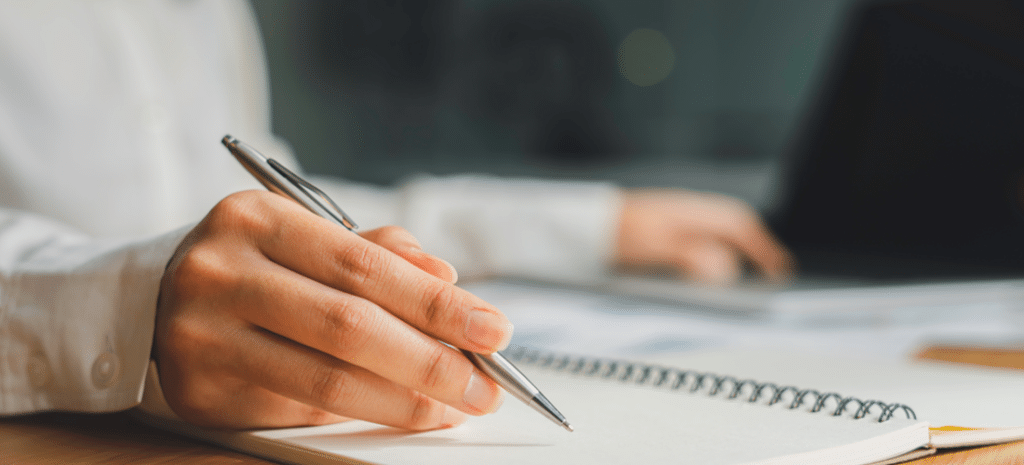 a hand poised and ready to write in a notebook