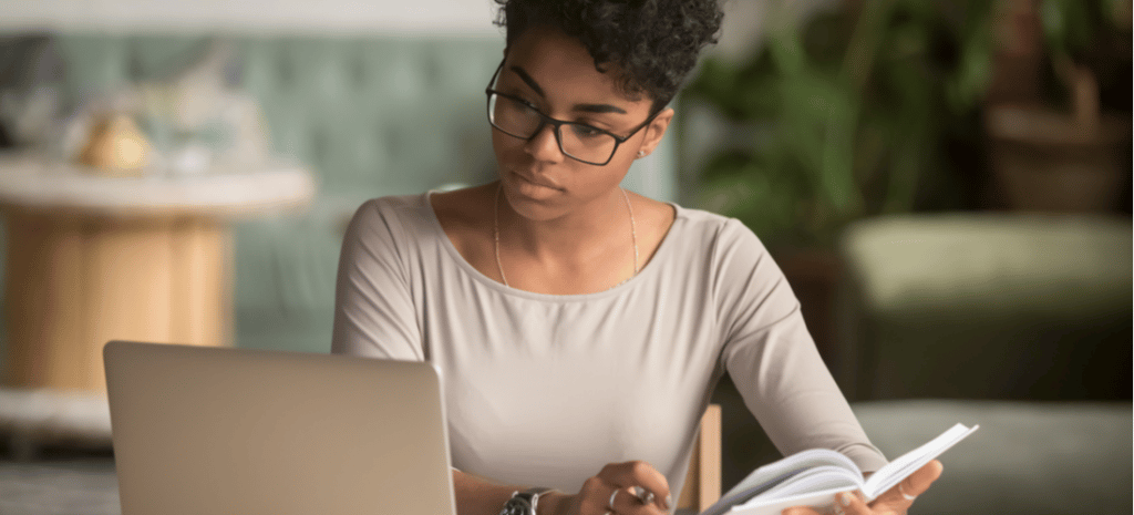 Woman sitting at desk learning WordPress looking at laptop and notebook