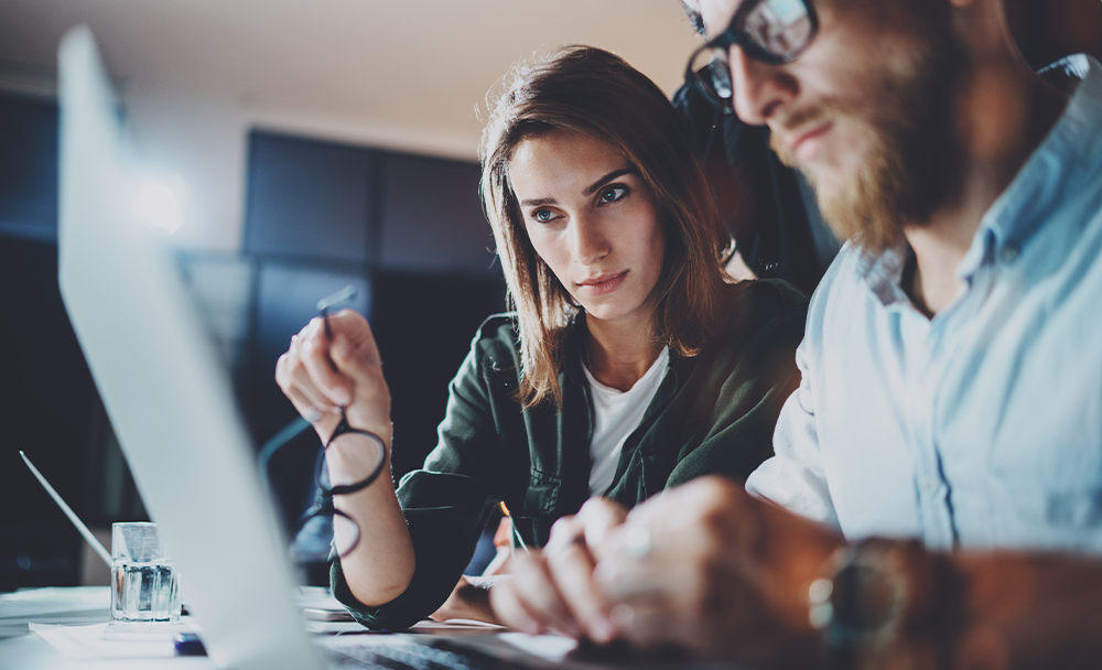 Two people looking at a computer screen, working on a website together