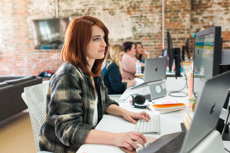 a woman with red hair works at a desk