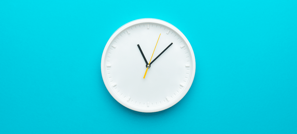 white analog clock with black hands on a blue background