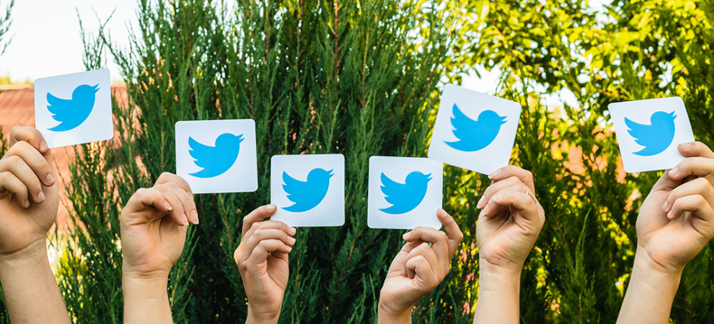 hands holding up multiple pieces of card stock with the Twitter logo