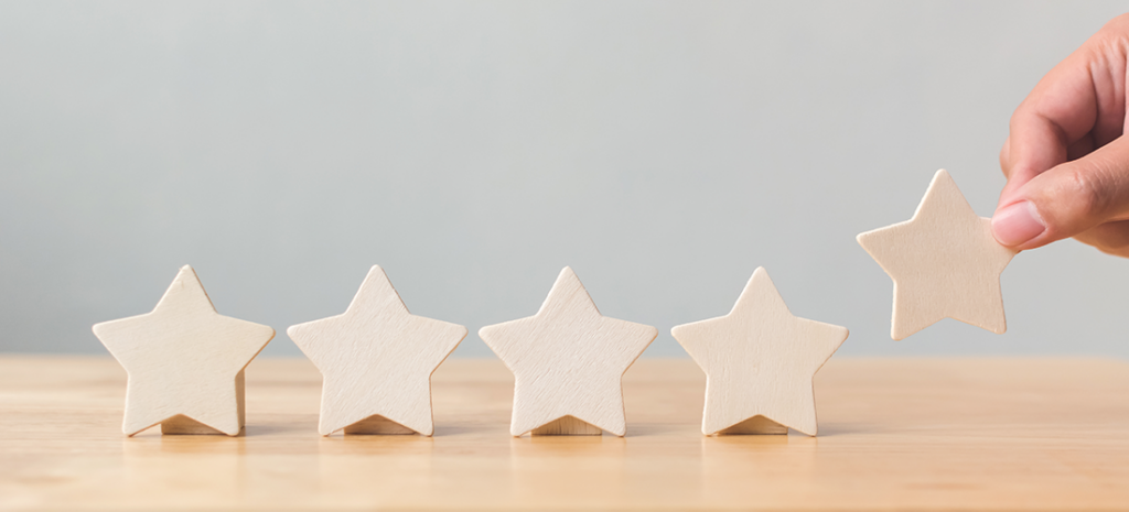 the secret to gaining customer loyalty. a hand places a fifth wooden star in a line of five stars