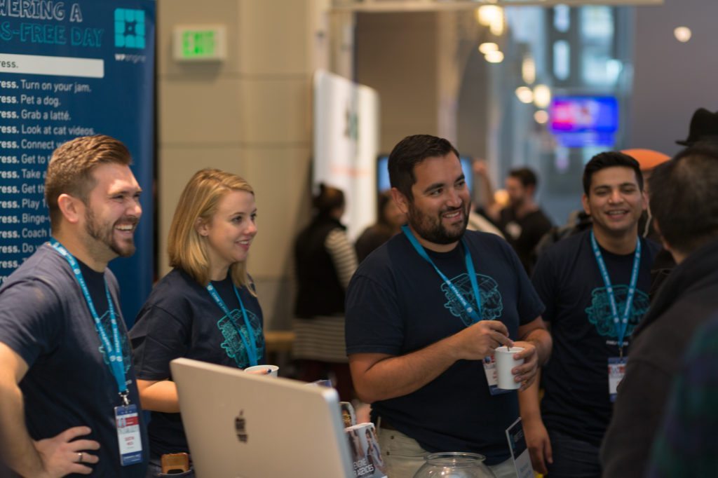 WP Engine employees Dustin Meza, Rachel Graham, John Gamboa, and Cidney Valadez gather around the WP Engine booth to chat with WCUS attendees. 