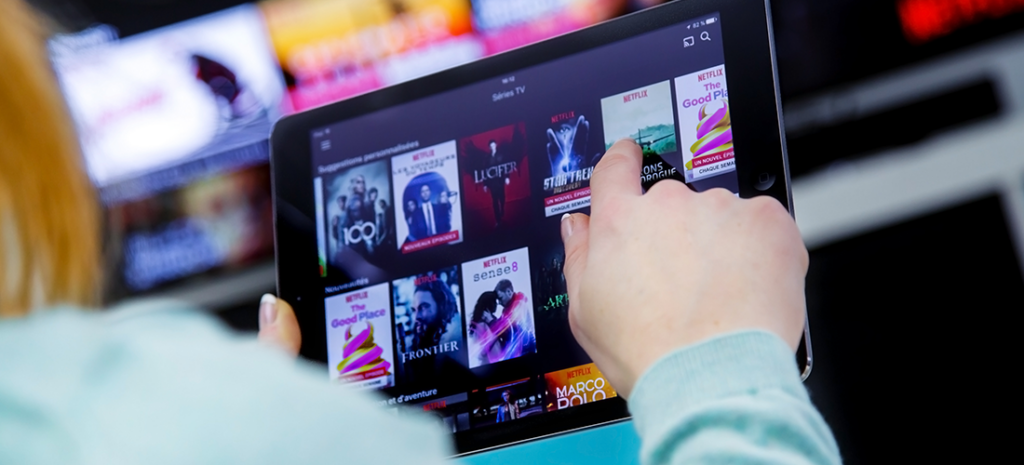 a person using a tablet views the thumbnails of potential shows or movies they can watch via a streaming platform