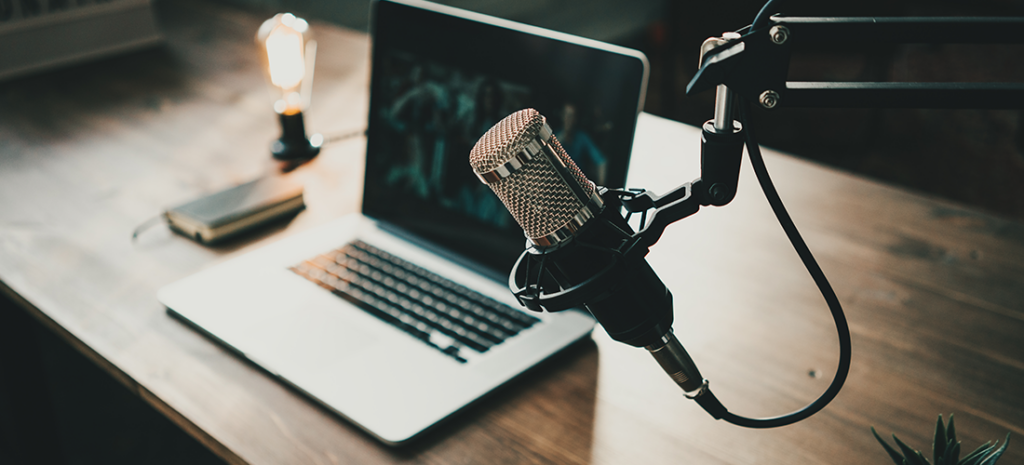 best marketing podcasts. Image shows an in-home podcast studio with a laptop , a light, and a microphone