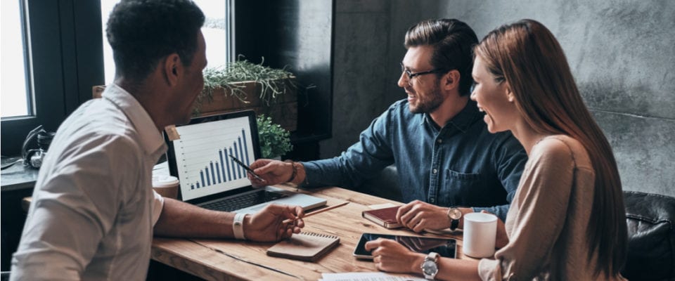 Group of young confident business people analyzing data using computer and smiling while working in the office