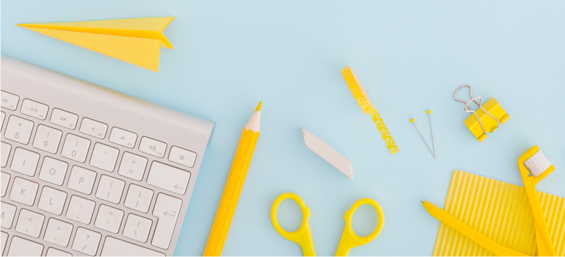 Image of a keyboard with yellow scissors and desk items
