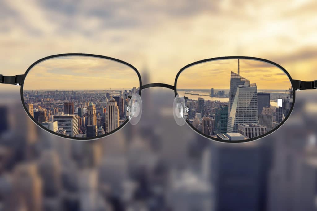 a blurry image of a city skyline is viewed clearly through the lenses of a pair of glasses
