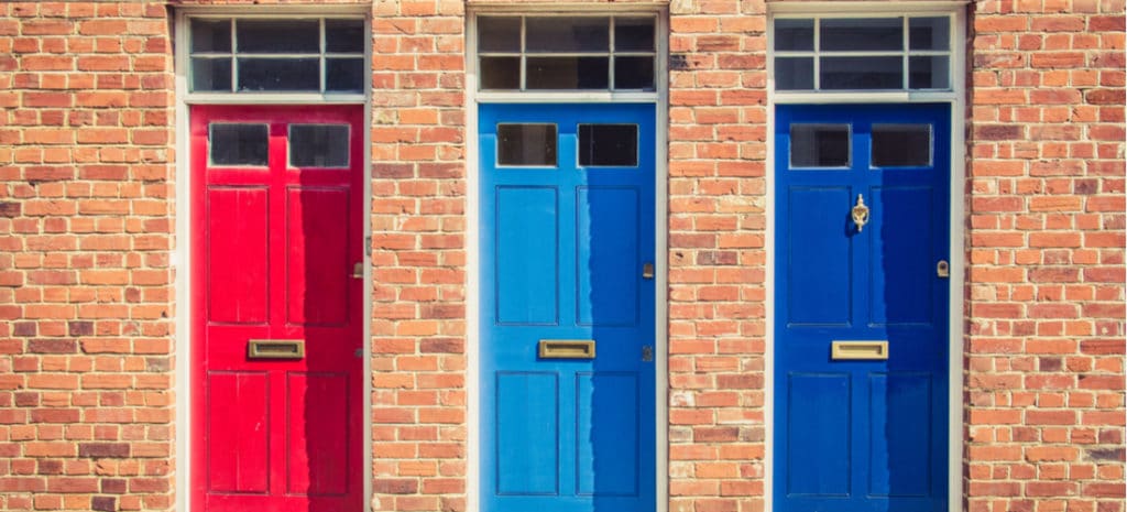 A red, light blue, and dark blue door on a brick building