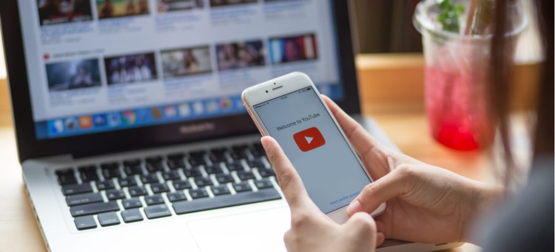 Person using YouTube on phone and laptop to optimize YouTube SEO