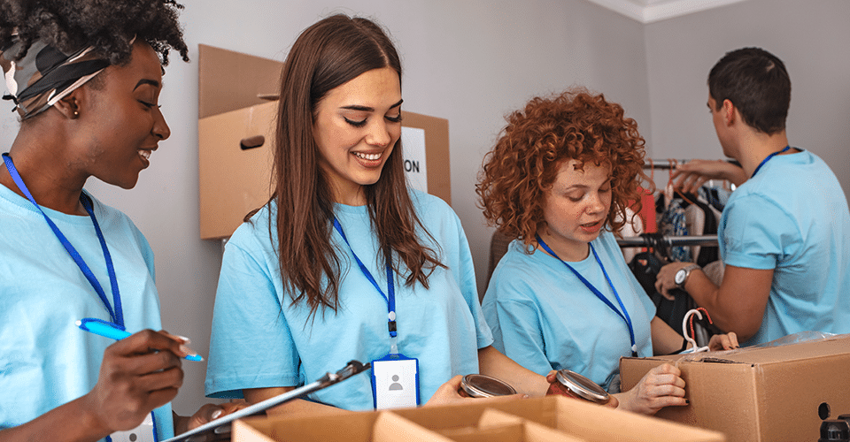 four volunteers pack boxes while working for a nonprofit organization