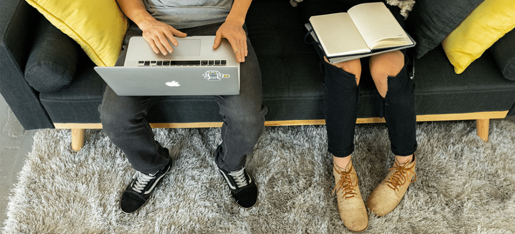 two developers discuss a website on a gray couch with yellow throw pillows