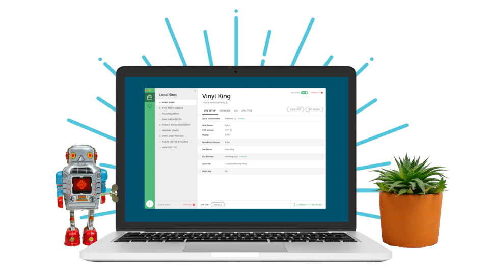 a small robot and a desktop planter flank a laptop screen that's open to Local, the WordPress development tool