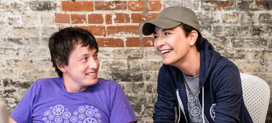 two people discuss a design project in front of a brick wall