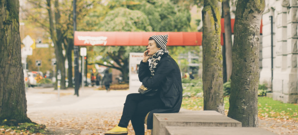 a woman takes a business call from a bench outdoors
