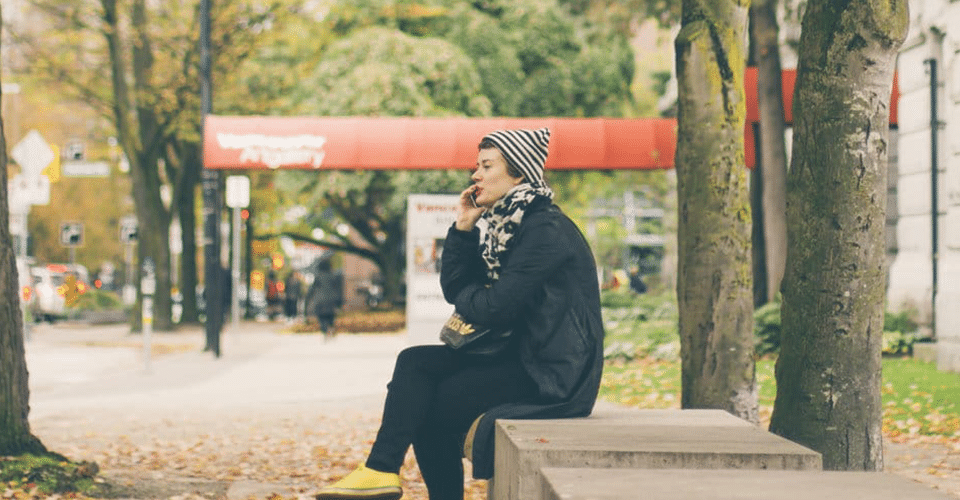 a woman takes a business call from a bench outdoors