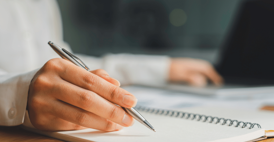 a hand poised and ready to write in a notebook