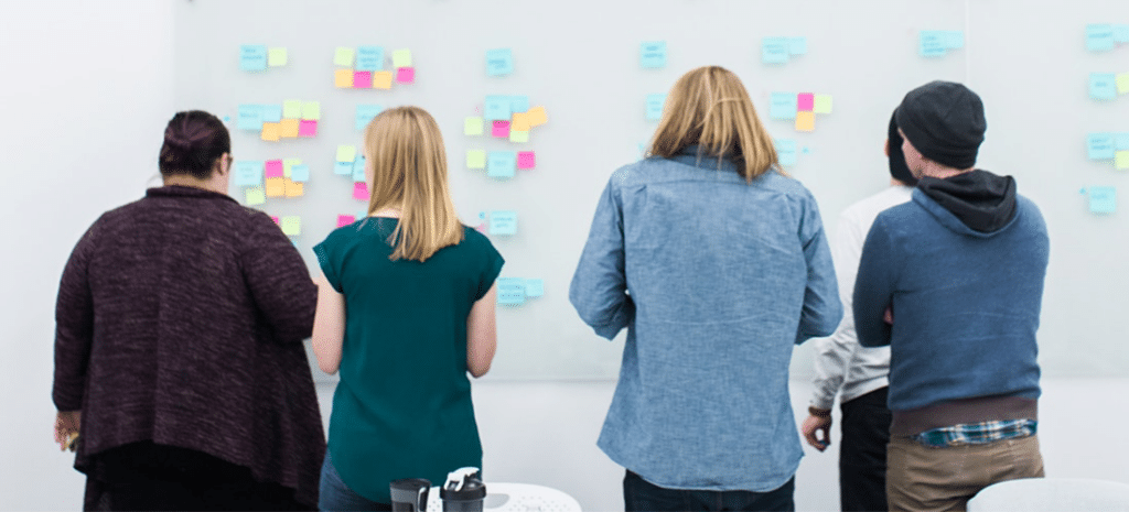 a marketing team defines their content strategy using sticky notes on a large white wall