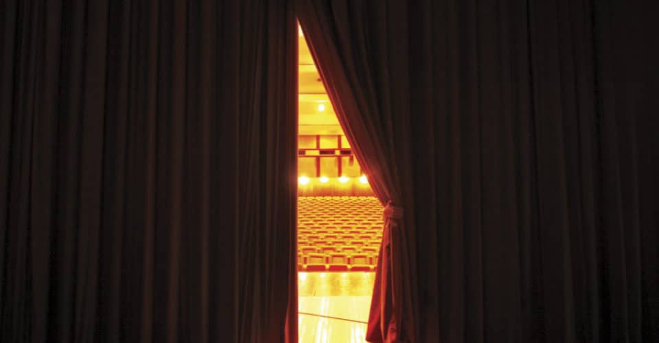 slightly open stage curtain looking out at theatre