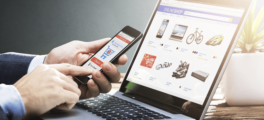a hand navigates a mobile eCommerce site in front of a laptop